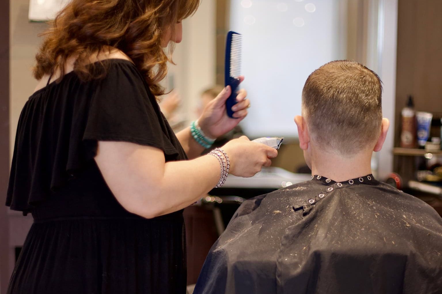 Stylist cutting a client's hair with clipper-over-comb at 18|8 Fine Men's Salons